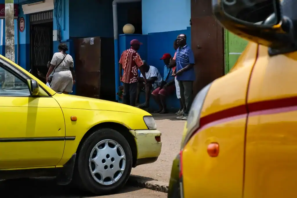 Two bright yellow taxis on a bustling São Tomé city street, demonstrating the main form of São Tomé transportation.