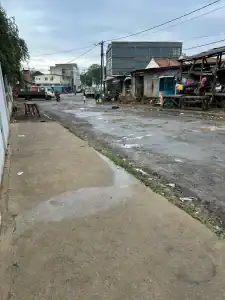 A bustling, unpaved street in São Tomé city center on a cloudy day, showing local market stalls and daily life.