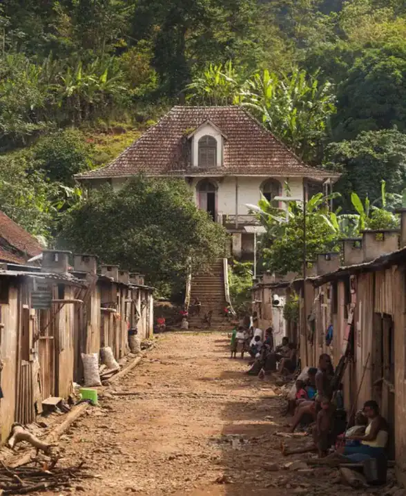 Workers’ street at a São Tomé roça, with a plantation house above wooden workers’ barracks in a green valley of Sao Tome Rocas