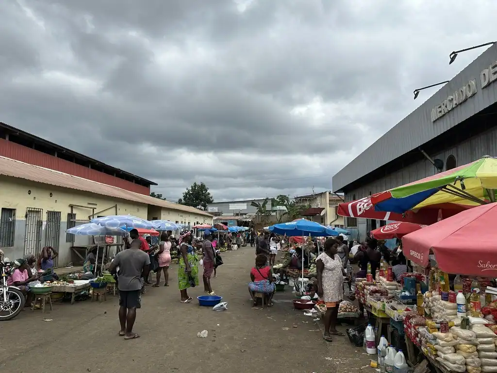 Bustling São Tomé street market scene with local vendors and shoppers under colorful umbrellas in the São Tomé City center. Essential image for any São Tomé City Guide.